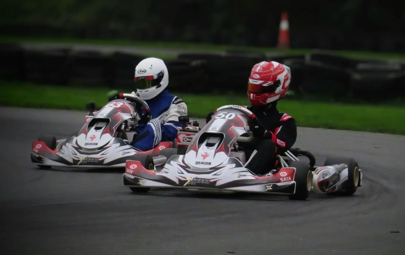 two xkarts karting around hooton park circuit in their white red and black livery drivers with a white arai and painted helmet.